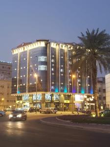 مساكن المنى Al Mona Residences Serviced Apartments في جدة: مبنى كبير به سيارات تقف في موقف للسيارات