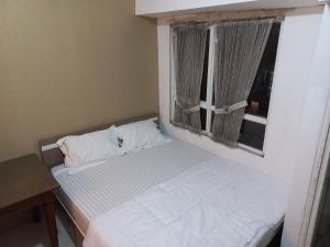Dormitorio pequeño con cama y ventana en J Room en Pondokcina