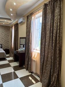 Royal Plus Hotel في يريفان: غرفة نوم بسرير ونافذة مع ستائر