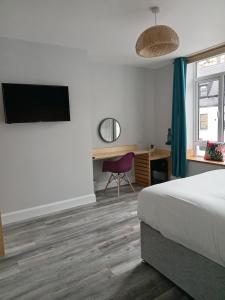 a bedroom with a bed and a desk with a tv at No.5 in Derry Londonderry