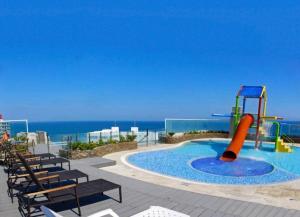 una piscina con tobogán, sillas y el océano en apartamento con vista al mar, en Santa Marta