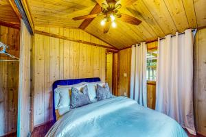 1 dormitorio con 1 cama azul y ventilador de techo en The Cabin at Monaville, 