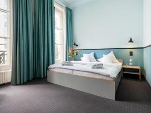 a bedroom with a large bed with green curtains at Aussen Alster Hotel in Hamburg