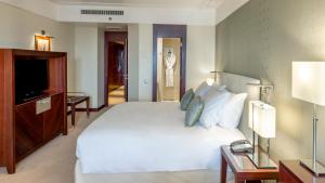 una camera da letto con un grande letto bianco e una televisione di Crowne Plaza Porto, an IHG Hotel a Porto