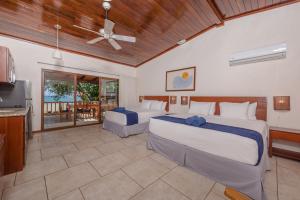 a bedroom with two beds and a television and a balcony at The Coast Beachfront Hotel in Tamarindo