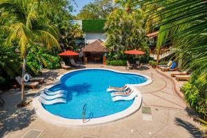 an overhead view of a swimming pool with people laying around it at The Coast Beachfront Hotel in Tamarindo