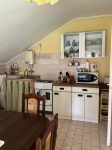 a kitchen with white cabinets and a table at Dózsa apartman in Hajdúszoboszló