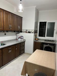 una cucina con armadi in legno e tavolo di Appartement boulaàyoun de luxe à louer nador 2 a Nador