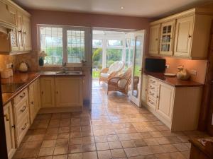 a kitchen with white cabinets and a tiled floor at Bedw Arian Cottage in Benllech
