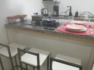 a kitchen counter with two chairs and a stove at Deslumbrante Apartamento Central in Curitiba