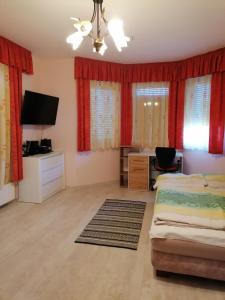 a bedroom with two beds and a tv and red curtains at Anna Vendégház in Balatonőszöd