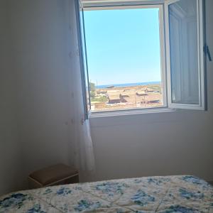 1 dormitorio con cama y ventana con vistas a la playa en Homem de Ferro en Alvor