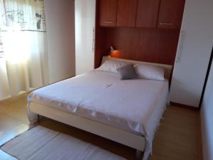 1 dormitorio con 1 cama blanca y ventana en Apartments with a parking space Kraj, Pasman - 8372 en Tkon