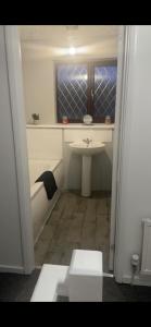 a bathroom with a sink and a toilet and a window at 5 bedroom modern detached house in Morriston