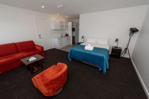 a living room with a bed and a red couch at Tekapo Lakefront Apartments in Lake Tekapo