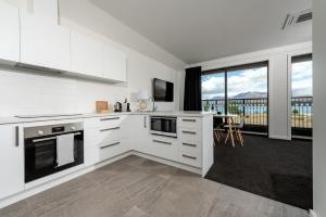 a kitchen with white cabinets and a large window at Tekapo Lakefront Apartments in Lake Tekapo
