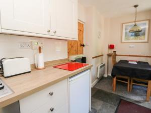 cocina con armarios blancos y encimera roja en Crinan Canal Cottage No8, en Lochgilphead