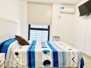 1 dormitorio con 1 cama con manta azul y blanca en Vow en Villa Carlos Paz