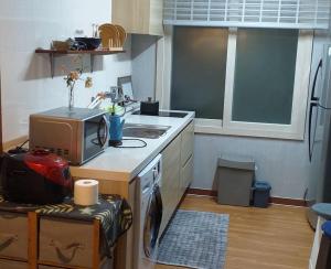 uma cozinha com um fogão, um lavatório e um micro-ondas em SoGoBe Pension em Jeju