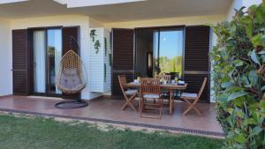 un patio con mesa, sillas y ventanas en Palm House Alvor, en Alvor