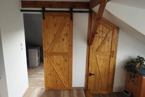 an attic room with a pair of wooden doors at Apartmán U Borovice in Bílá Třemešná