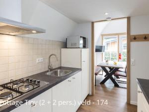 a kitchen with a sink and a stove top oven at Beautiful cottage with dishwasher, in a holiday park not far from Giethoorn in De Bult
