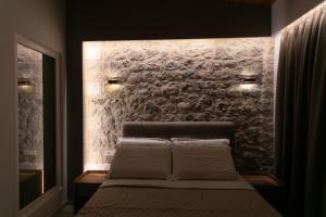 1 dormitorio con 1 cama con pared de piedra en Elais Luxury Villas, en Parga