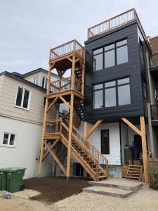 a black house with a wooden staircase next to a house at Yin et Yang in Sainte-Anne-de-Beaupré