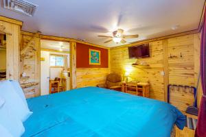 1 dormitorio con 1 cama azul y paredes de madera en Cedaredge Lodge Cabin 4 en Cedaredge