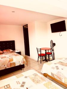 a bedroom with two beds and a table and chairs at Hospedaje Nápoles in Trujillo