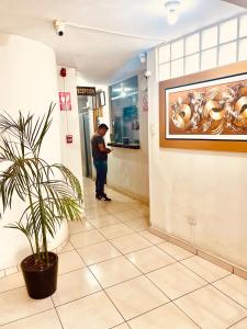 un hombre parado en el pasillo de un hospital con una planta en Hospedaje Nápoles en Trujillo