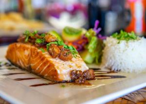 a plate of food with a piece of fish and rice at Mar Paraiso Queen in Acapulco