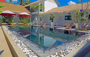 a swimming pool in a resort with chairs and umbrellas at ERCAN BOUTiQUE in Siem Reap