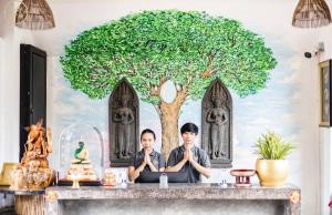 Due persone sedute a un tavolo di fronte ad un albero di ERCAN BOUTiQUE a Siem Reap