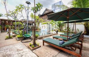 a patio with chairs and an umbrella and a pool at Green BOUTiQUE in Siem Reap