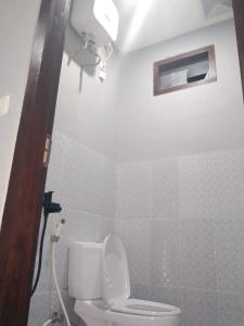 a white bathroom with a toilet and a window at Mount Rinjani Guest House in Sajang