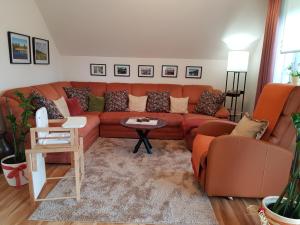 a living room with an orange couch and chairs at Ferienwohnung Monschauer Land in Monschau