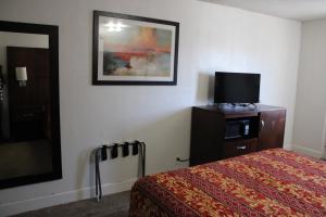 a hotel room with a bed and a flat screen tv at Flagstaff Motel in Flagstaff