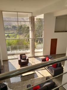 a living room with couches and a large window at Casa de Campo Las Tujas in Lunahuaná