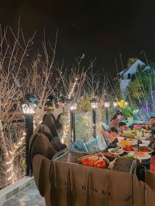 una mesa llena de comida con gente sentada alrededor en villa Trung Nghĩa 5, en Da Lat