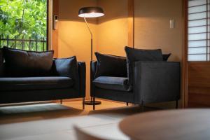 a living room with two black chairs and a lamp at Tsukasa Ryokan in Saga
