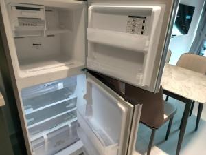 een lege koelkast met de deur open en een tafel bij DangaBay SeaView 4pax with Netflix WiFi in Johor Bahru