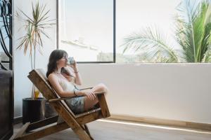 Una mujer sentada en una silla mirando por la ventana en Casa Fenix, en Sayulita