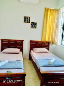 two twin beds in a room with a window at Qalya Homestay 1 @ Kota Bharu in Kota Bharu