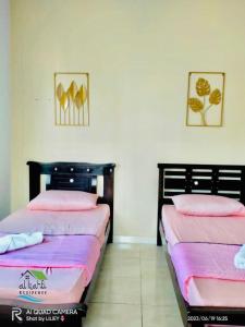 twee bedden naast elkaar in een kamer bij Qalya Homestay 1 @ Kota Bharu in Kota Bharu