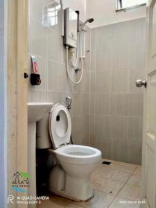 een badkamer met een toilet en een telefoon aan de muur bij Qalya Homestay 1 @ Kota Bharu in Kota Bharu