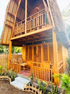 Cette grande maison en bois dispose d'un balcon et d'une terrasse couverte. dans l'établissement SAJA Cottage, Gili Meno, à Gili Meno