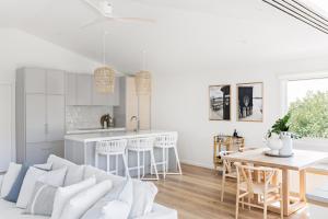 a white kitchen and living room with a couch and a table at Cape Beach House in Byron Bay