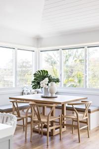 a dining room with a table and chairs and windows at Cape Beach House in Byron Bay