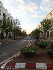 an empty street in a town with trees and buildings at La Maison Haute Larache Morocco in Larache